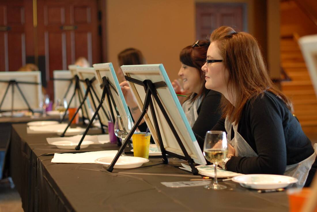 Picture of people painting and drinking wine at a painting class